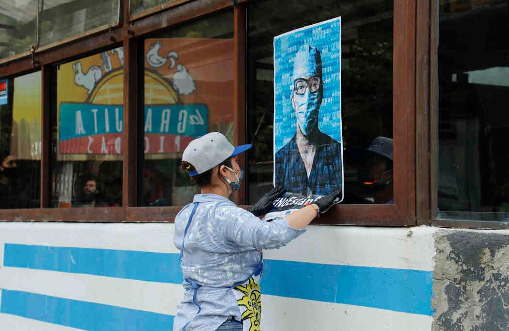 En la vía a la calera, en Bogotá, un empleado de un restaurante pega el afiche en una ventana del local. Este tenía dos caras y aquí muestra el rostro de un médico hecho con las cientos de fotos que se tomaron. 