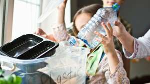 Madre enseñando a sus hijos a separar residuos de plástico, vidrio y papel en casa