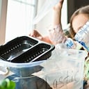 Madre enseñando a sus hijos a separar residuos de plástico, vidrio y papel en casa