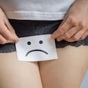 Vaginal or menstrual problems concept. Young woman holds paper with SOS above crotch.