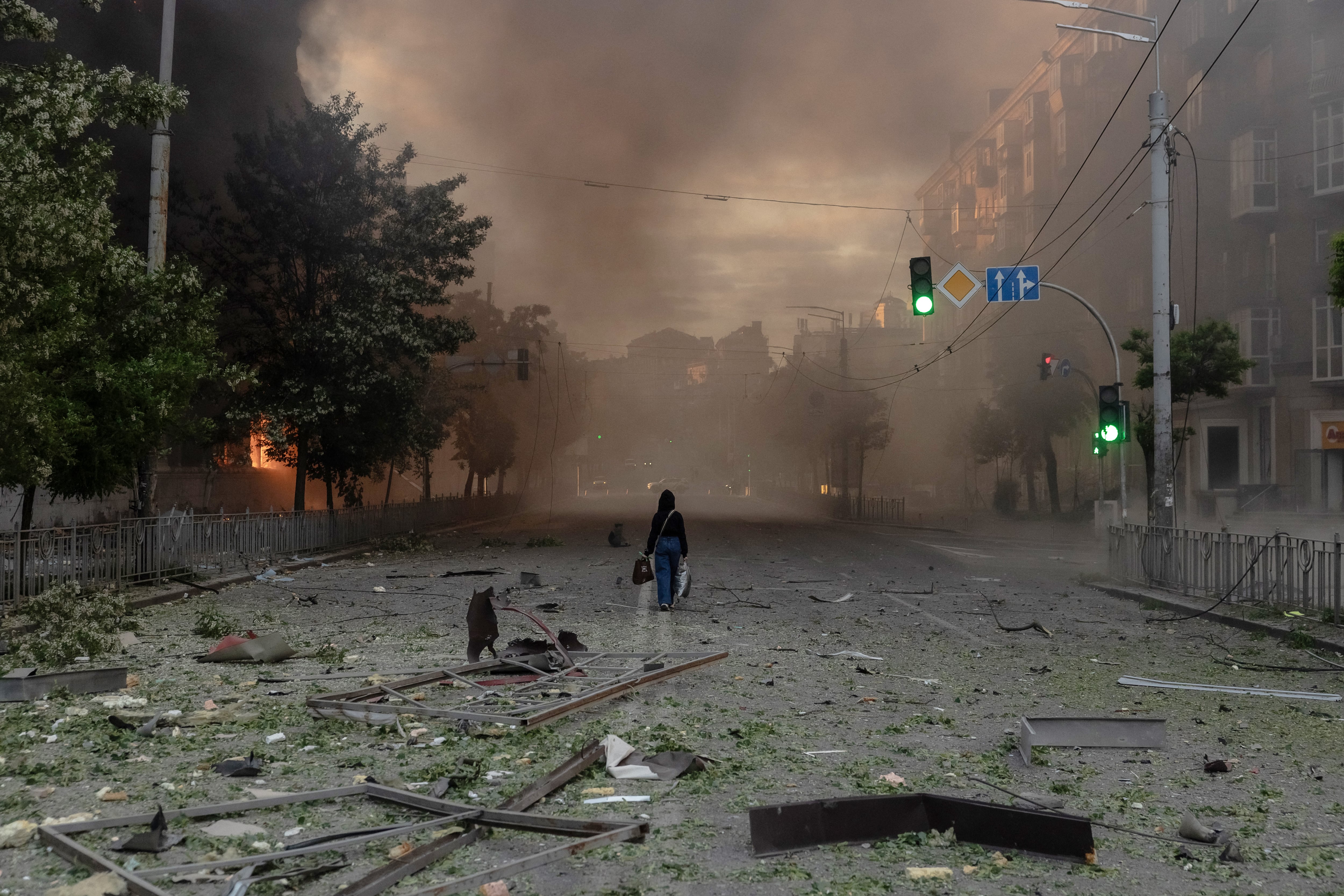 Una mujer camina por una calle llena de humo junto a edificios gravemente dañados tras los ataques rusos en Kiev el 24 de mayo de 2026, en el contexto de la invasión rusa de Ucrania. Un potente ataque con misiles balísticos sacudió Kiev a primera hora del 24 de mayo, según informaron las autoridades, hiriendo al menos a cinco personas después de que Moscú amenazara con represalias por los ataques en el este de Ucrania, territorio ocupado por Rusia. (Foto de Roman PILIPEY / AFP)