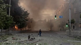 Una mujer camina por una calle llena de humo junto a edificios gravemente dañados tras los ataques rusos en Kiev el 24 de mayo de 2026, en el contexto de la invasión rusa de Ucrania. Un potente ataque con misiles balísticos sacudió Kiev a primera hora del 24 de mayo, según informaron las autoridades, hiriendo al menos a cinco personas después de que Moscú amenazara con represalias por los ataques en el este de Ucrania, territorio ocupado por Rusia. (Foto de Roman PILIPEY / AFP)
