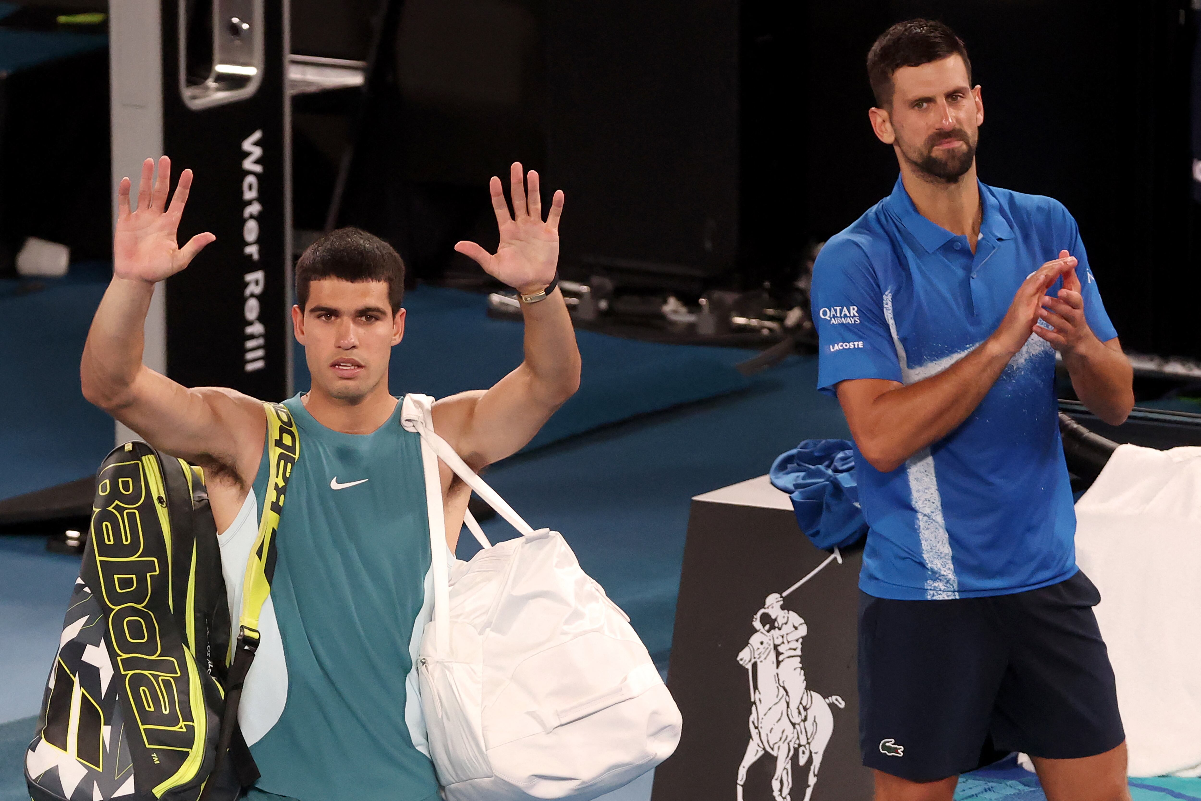 El español Carlos Alcaraz (izq.) agradece a los espectadores mientras abandona la pista tras su derrota ante el serbio Novak Djokovic (dcha.) en el partido de cuartos de final individual masculino de la décima jornada del Abierto de Australia de tenis en Melbourne, el 22 de enero de 2025.