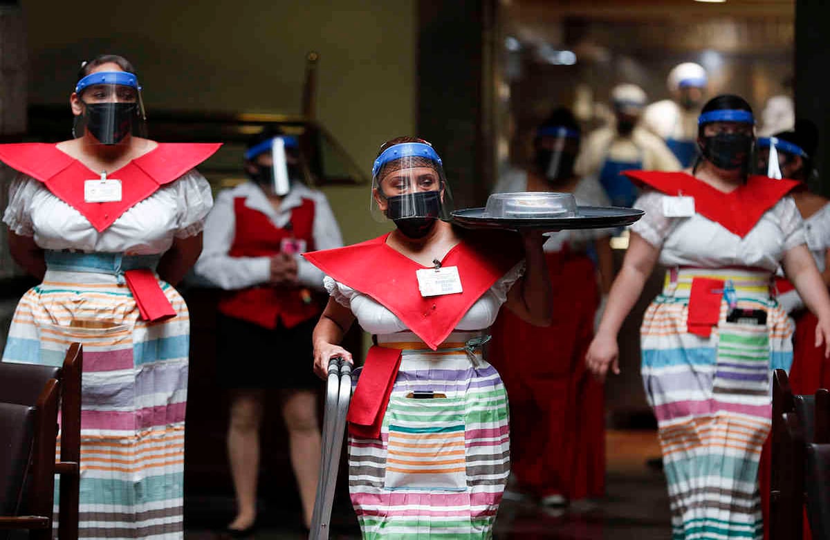Esta es la nueva normalidad en los restaurantes de Ciudad de México. Una camarera con máscara y protector facial lleva una orden en "Sanborns of the Azulejos", punto gastronómico del centro de la capital mexicana. Imagen del miércoles 1 de julio. Foto: Eduardo Verdugo / AP 