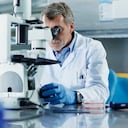Scientist looking through microscope in research laboratory