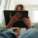 28 de mayo de 2022, Berlín: Una niña se sienta en el sofá y mira la tableta de sus padres. Foto: Annette Riedl/dpa (Foto de Annette Riedl/Picture Alliance vía Getty Images)
