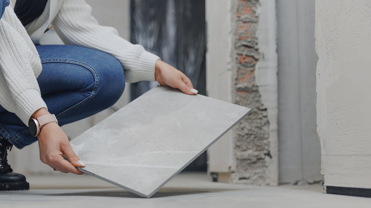 El arquitecto diseñador comprueba y acepta el trabajo del maestro alicatador sobre la colocación de baldosas de porcelana en el suelo.