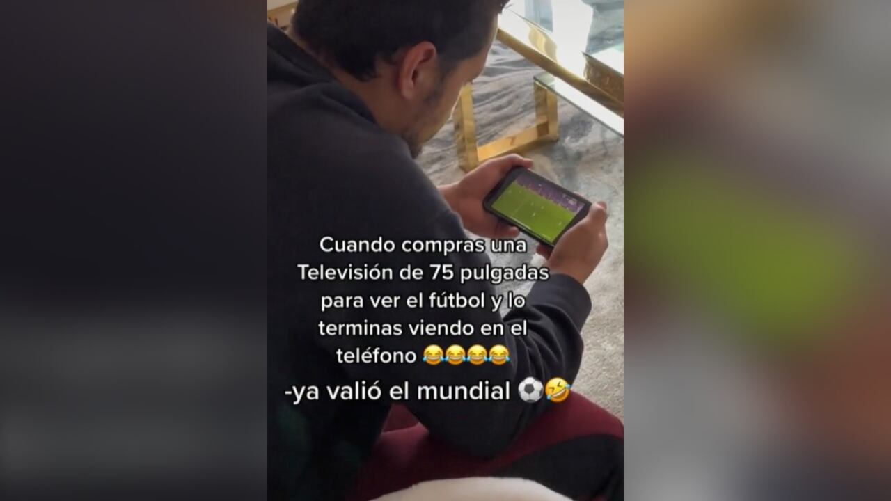 El hombre ve el partido en la sala, mientras su hija está sentada a su lado viendo dibujos animados.