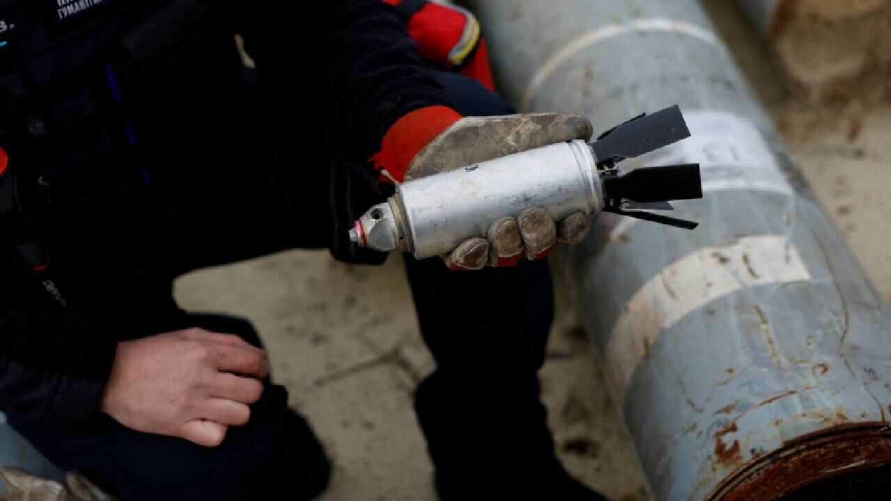 Militar ucraniano sostiene una bomba de racimo desactivada.