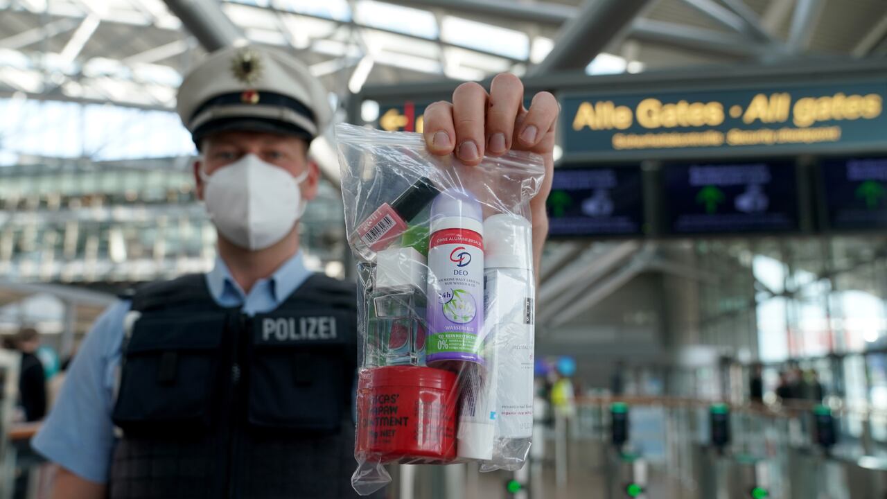 Un policía sostiene una bolsa con cerradura que contiene cosméticos que pueden llevarse en el equipaje de mano en un vuelo, fuera del control de seguridad del aeropuerto de Hamburgo.