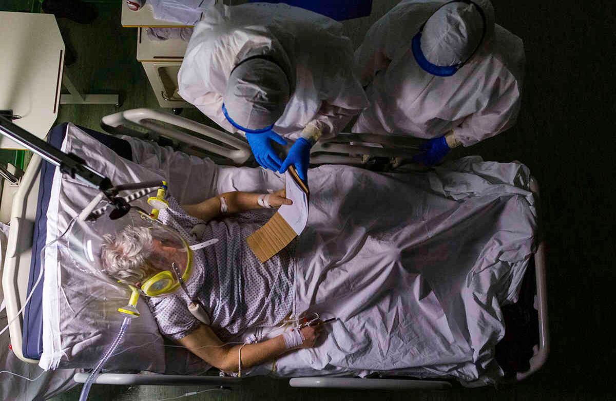 El doctor Giovanni Passeri, a la izquierda, con su asistente médico Mariaconcetta Terracina, hace que el paciente Mario de 82 años lea su nota sobre sus condiciones médicas, durante un examen de rutina, en la sección de covid-19 del Hospital Mayor de Parma, norte de Italia, el 8 de abril. Mario ha estado bajo ventilación CPAP (presión positiva continua de aire) para la cabeza y solo pudo comunicarse por escrito porque el silbido del oxígeno no le permitía escuchar la voz del doctor. Foto:Domenico Stinellis/ AP