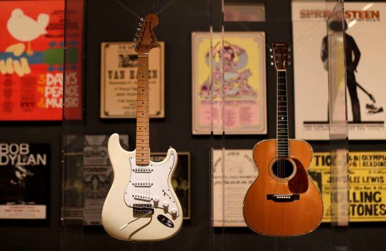 Las guitarras utilizadas por Jimi Hendrix, a la izquierda, y Eric Clapton, a la derecha se exhiben con carteles de conciertos y albumes en el fondo. FOTO: Seth Wenig / AP