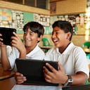 Los niños de la escuela en uniformes en clase con tabletas