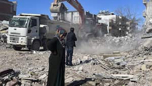 Los padres de Taha Erdem, la madre Zeliha Erdem, a la izquierda, y el padre, Ali Erdem, junto a los escombros del edificio donde Tahan quedó atrapado después del terremoto del 6 de febrero en Adiyaman, Turquía.