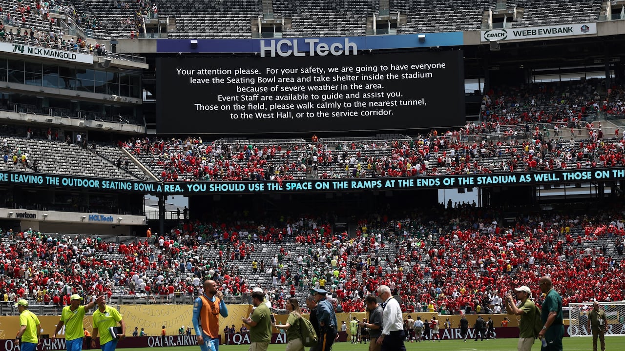 Staff's members evacuate the pitch following a storm alert during the FIFA Club World Cup 2025 Group A football match between Brazil's Palmeiras and Egypt's Al-Ahly at the MetLife stadium in East Rutherford, New Jersey on June 19, 2025. (Photo by FRANCK FIFE / AFP)