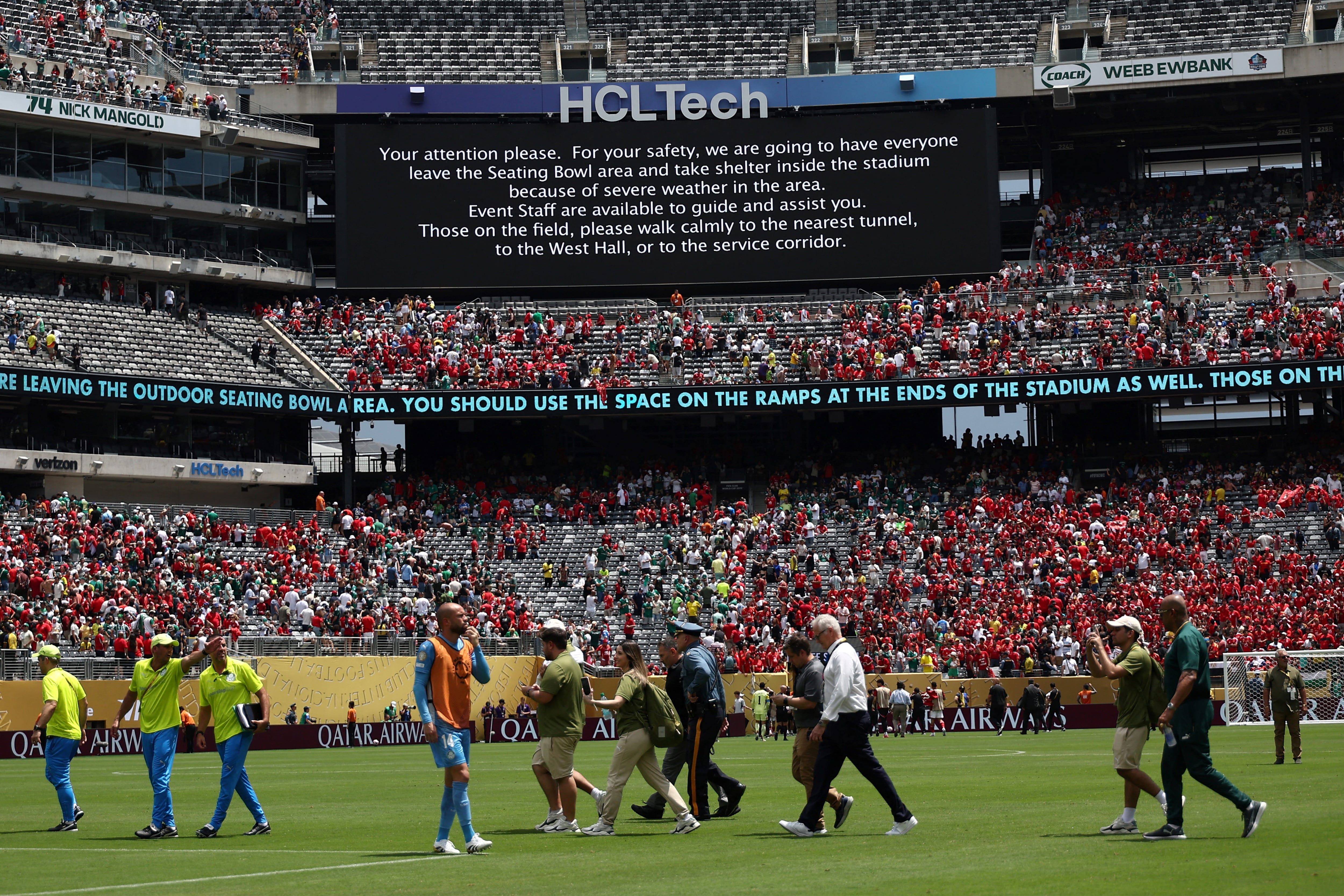 Staff's members evacuate the pitch following a storm alert during the FIFA Club World Cup 2025 Group A football match between Brazil's Palmeiras and Egypt's Al-Ahly at the MetLife stadium in East Rutherford, New Jersey on June 19, 2025. (Photo by FRANCK FIFE / AFP)