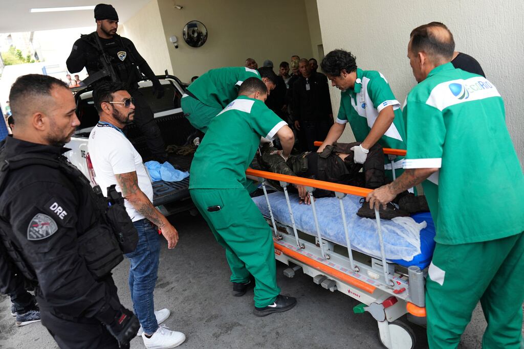 Trabajadores del Hospital Getulio Vargas trasladan a una persona herida en camilla tras ser trasladada en un camión policial durante un operativo contra presuntos narcotraficantes en la favela Complexo do Alemao, donde opera la organización criminal "Comando Vermelho", en Río de Janeiro, el martes 28 de octubre de 2025. (Foto AP/Silvia Izquierdo)