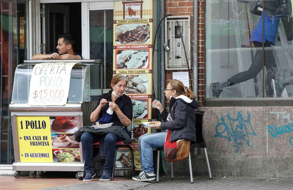 Dos señoras comiendo en la calle sin ninguna protección al frente del centro comercial Subazar.