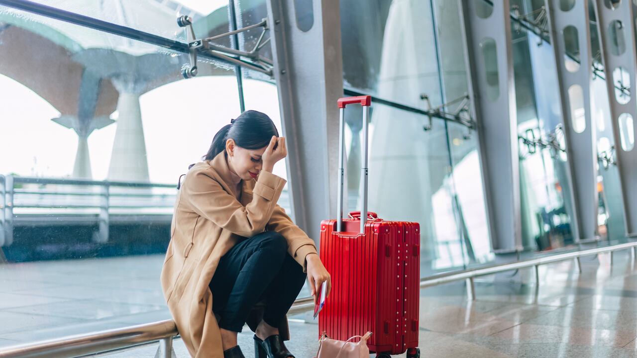 Sad and tired woman sitting in the airport - missed or cancelled flight concept