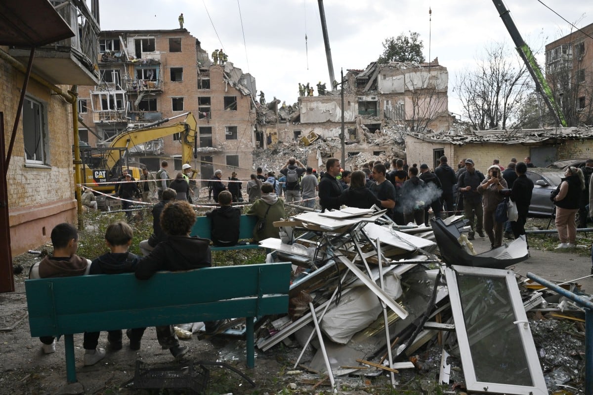 Residentes locales observan a los equipos de rescate trabajar en un edificio residencial de varias plantas destruido tras un ataque aéreo ruso en Pryluky el 7 de octubre de 2026