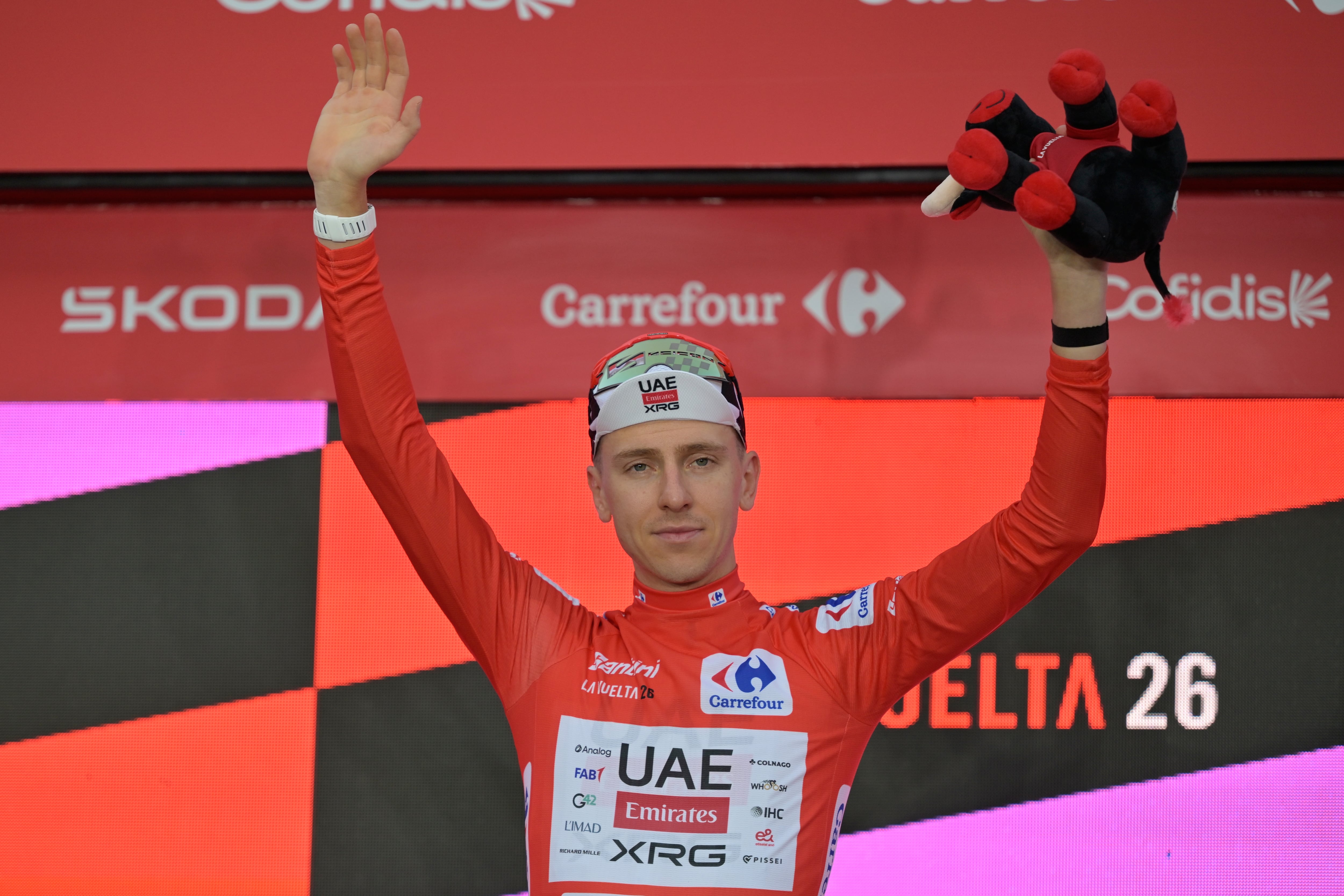 Slovenia's Tadej Pogacar, wearing the overall leader's red jersey celebrates on the podium after winning the first stage of the La Vuelta cycling race, a time trial with start and finish in Monaco, Saturday, Aug. 22, 2026. (AP Photo/Philippe Magoni)