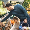 Vista lateral de cerca de una pareja de finales de los años 20 comprando algunas verduras en un supermercado local. Están recogiendo papas y cebollas que necesitarán para la cena. El tipo lleva una cesta de la compra.