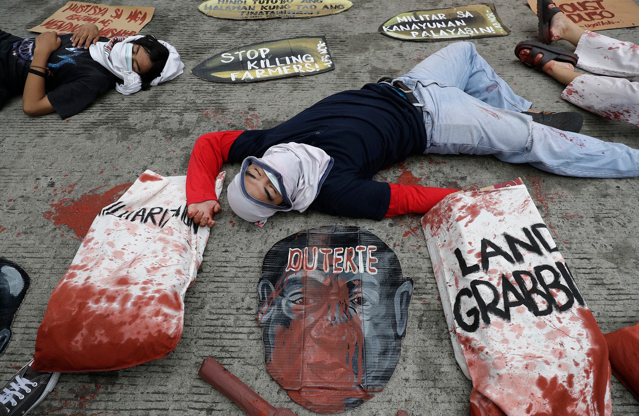 Los manifestantes recrean los asesinatos de manifestantes en 1987 y también pidieron al gobierno del presidente filipino Rodrigo Duterte que esté detrás de los recientes presuntos asesinatos de campesinos durante una manifestación el viernes 22 de enero de 2021 en Manila, Filipinas. Los agricultores y los activistas de izquierda llevaban máscaras para evitar la propagación del coronavirus mientras marchaban por el histórico Puente Mendiola cerca del Palacio Presidencial de Malacanang para conmemorar la masacre de 1987 por parte de las tropas gubernamentales de 13 manifestantes que buscaban la distribución justa de las tierras agrícolas. (Foto AP / Aaron Favila)