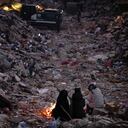 Miembros de una familia se mantienen calientes junto a una fogata mientras siguen a un equipo de rescate que busca a sus familiares entre un edificio destruido en Antakya, en el sur de Turquía, el miércoles 15 de febrero de 2023.