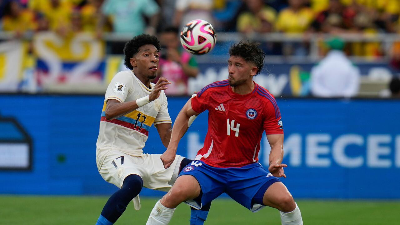El colombiano Johan Mojica, a la izquierda, y el chileno Felipe Loyola disputan el balón durante un partido de clasificación para la Copa Mundial de la FIFA 2026 en el estadio Metropolitano Roberto Meléndez en Barranquilla, Colombia, el martes 15 de octubre de 2024. (Foto AP/Fernando Vergara)