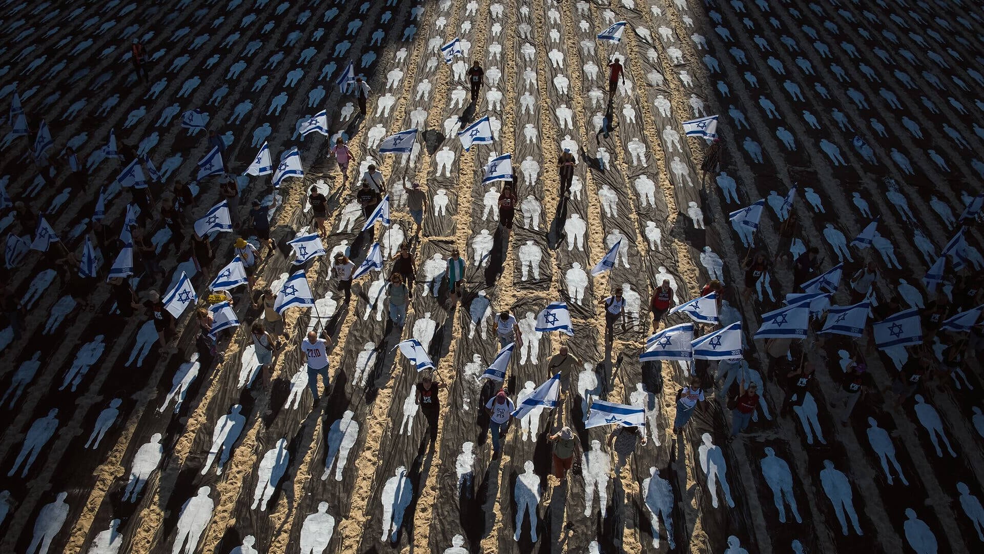 Personas que llevan banderas israelíes caminan a través de una instalación que marca el tercer aniversario del 7 de octubre de 2023, cuando Hamás atacó a Israel. Playas de Tel Aviv, Israel, el miércoles 7 de octubre de 2026.