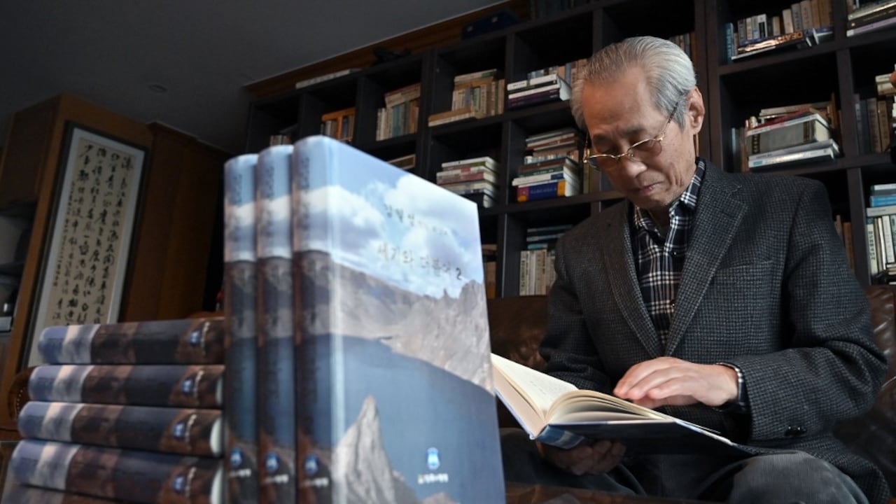 Esta foto tomada el 30 de abril de 2021 muestra al editor surcoreano Kim Seung-kyun mirando una copia de las memorias del fundador de Corea del Norte, Kim Il Sung, en ocho volúmenes, titulada "Con el siglo", durante una entrevista con la AFP en su casa de Goyang. Foto de Jung Yeon-je / AFP