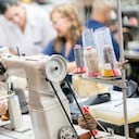 Trabajadora de fabricación femenina que trabaja en una fábrica de calzado usando una máquina de coser industrial