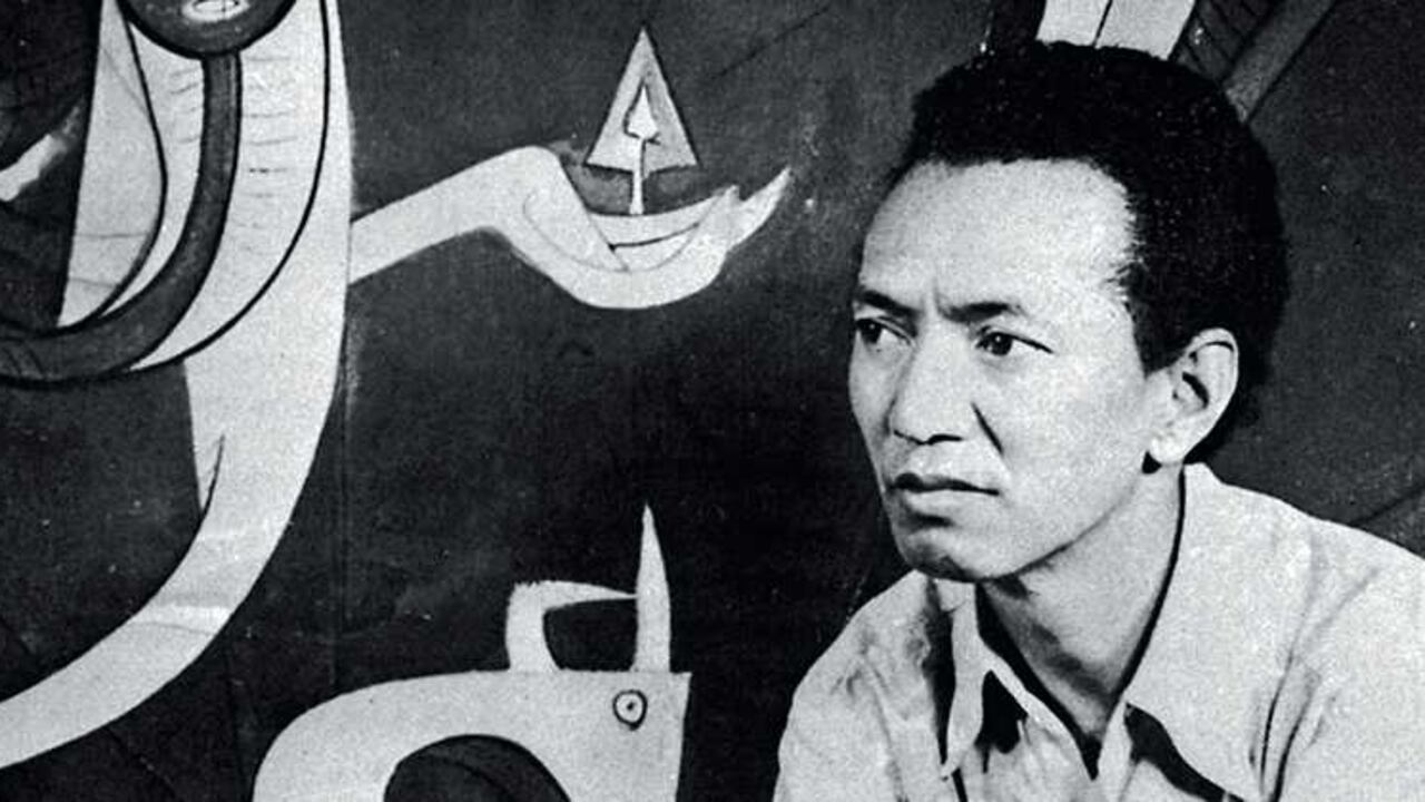 Wilfredo Lam sentado frente a una de sus obras en La Habana, Cuba, en 1963.