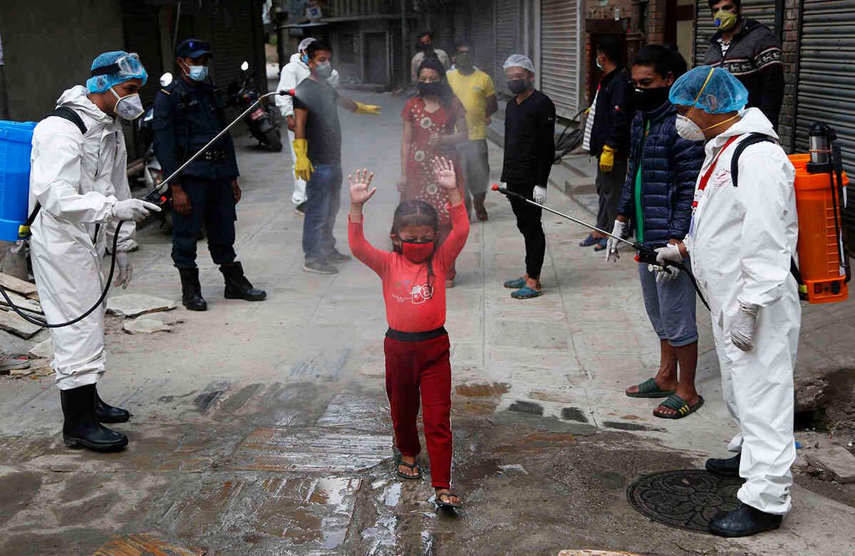 Una niña nepalesa es rociada con desinfectantes al llegar a la repartición de alimentos gratuitos distribuidos por trabajadores sociales, durante el encierro para controlar la propagación del  coronavirus en Katmandú. La imagen es del 3 de mayo. Nepal extendió el cierre de la frontera internacional hasta el 13 de mayo. Foto: Niranjan Shrestha/ AP