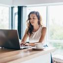 Mujer que usa la computadora portátil mientras está sentado en casa.
