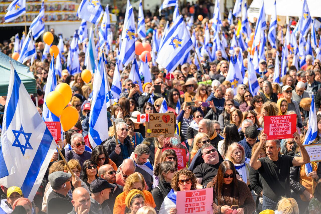 TEL AVIV, ISRAEL - FEBRUARY 26: A crowd watches a live feed from a funeral for members of the Bibas family on a screen in what's known as Hostages Square on February 26, 2025 in Tel Aviv, Israel. A funeral is being held for former hostages Shiri Bibas and her two young sons, Ariel and Kfir, whose bodies were returned to Israel from Gaza last week. At the time of their abduction from Kibbutz Nir Oz on October 7, 2023, Shiri was 32, Ariel was four, and Kfir was nine months old. Their father, Yarden Bibas, 34, was also taken by Hamas militants, but was released alive as part of the ceasefire agreement on 1 February. (Photo by Alexi J. Rosenfeld/Getty Images)