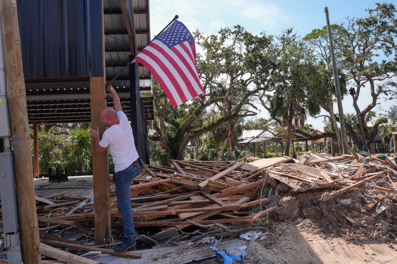 John Taylor coloca una bandera estadounidense en su propiedad destruida tras el huracán Helene, en Horseshoe Beach, Florida, el sábado 28 de septiembre de 2024. (Foto AP/Gerald Herbert)