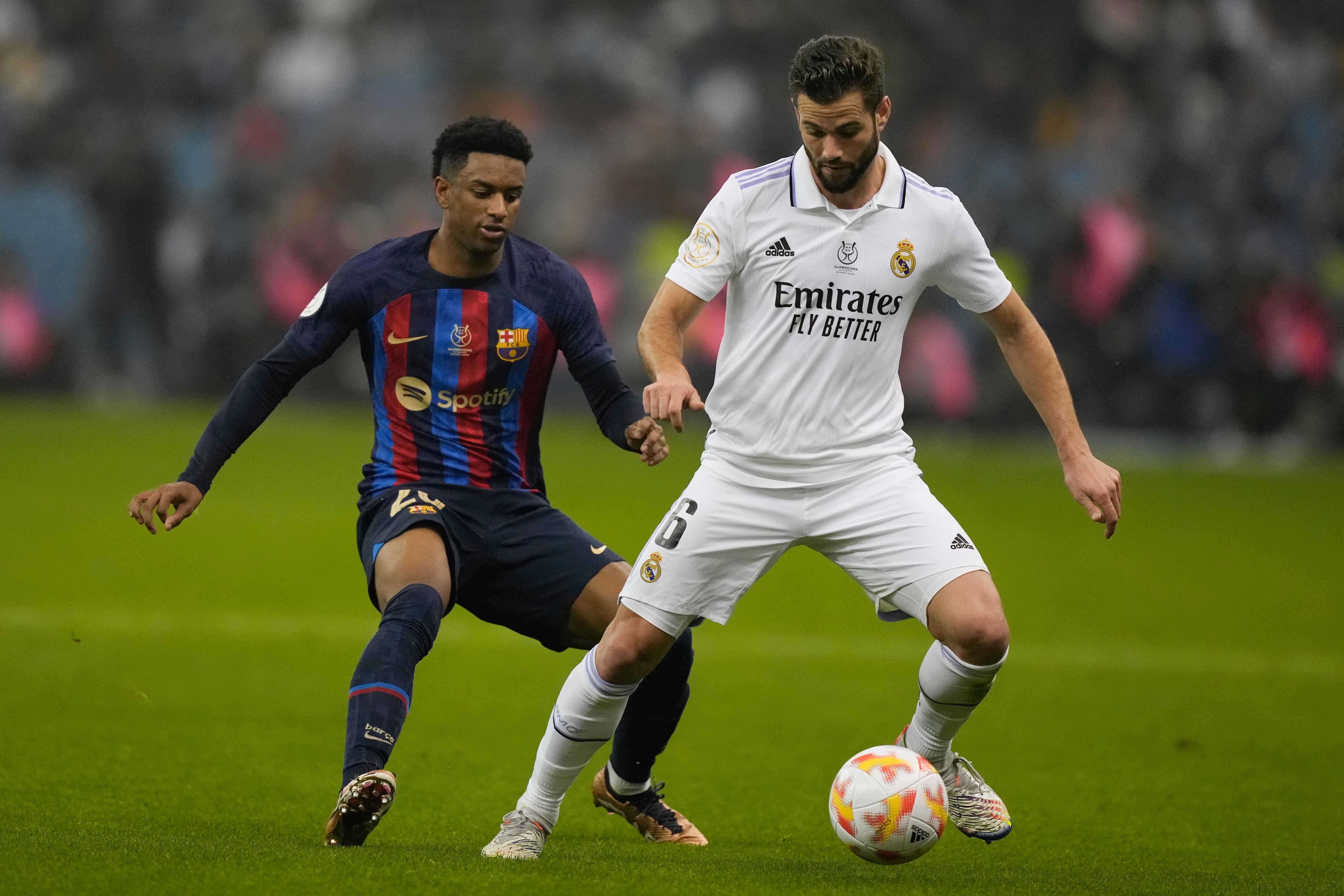 Barcelona's Alejandro Balde, left, and Real Madrid's Nacho fight for the ball during the final of the Spanish Super Cup between Barcelona and Real Madrid in Riyadh, Saudi Arabia, Sunday, Jan. 16, 2023. (AP Photo/Hussein Malla)