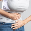 Mujer joven con dolor de estómago doloroso. Gastritis crónica. Calambres estomacales o menstruales. Concepto de hinchazón abdominal.