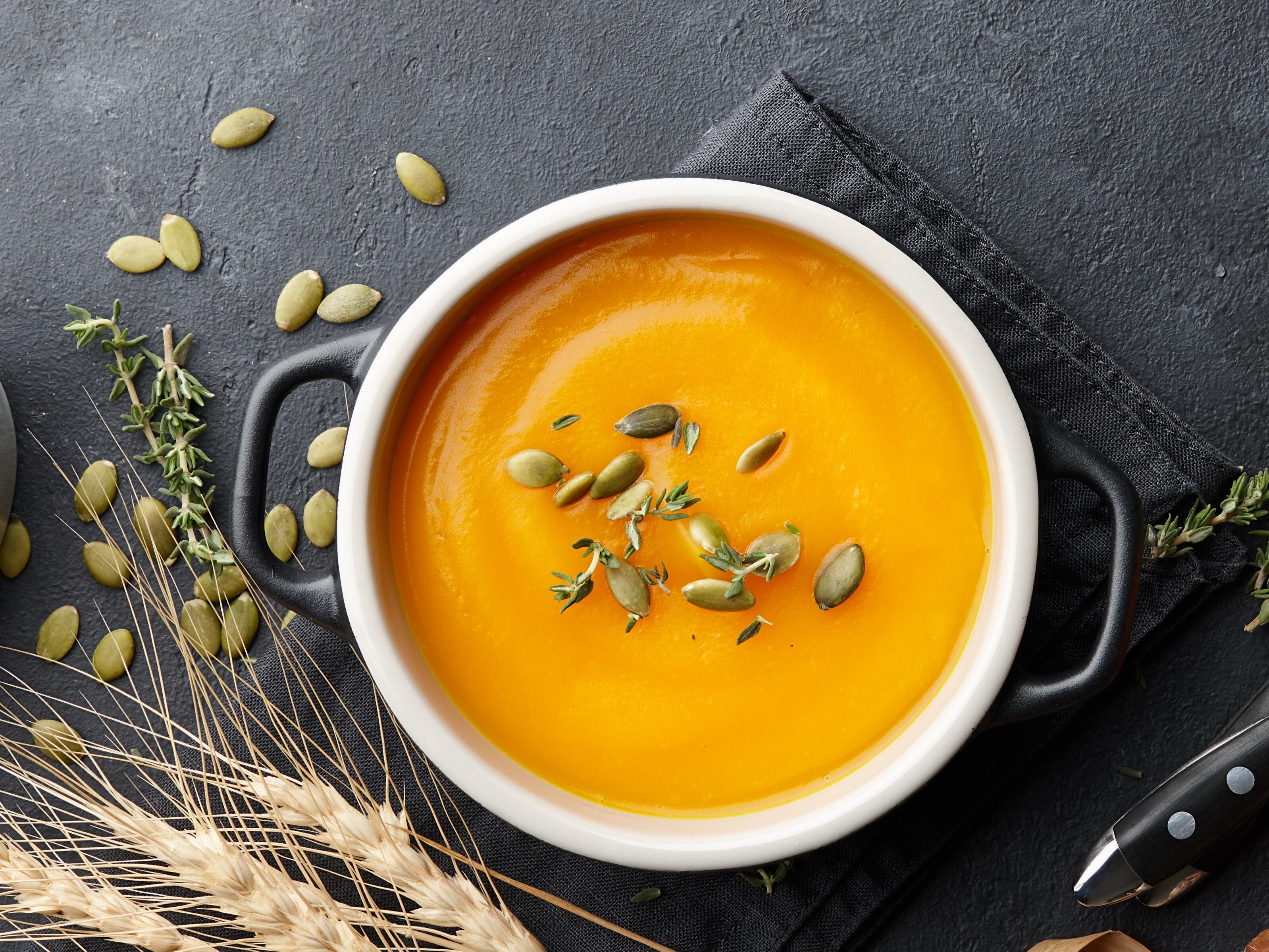 Sopa de calabaza con semillas de tomillo y calabaza sobre fondo negro. Auyama, ahuyama, alimentos, crema