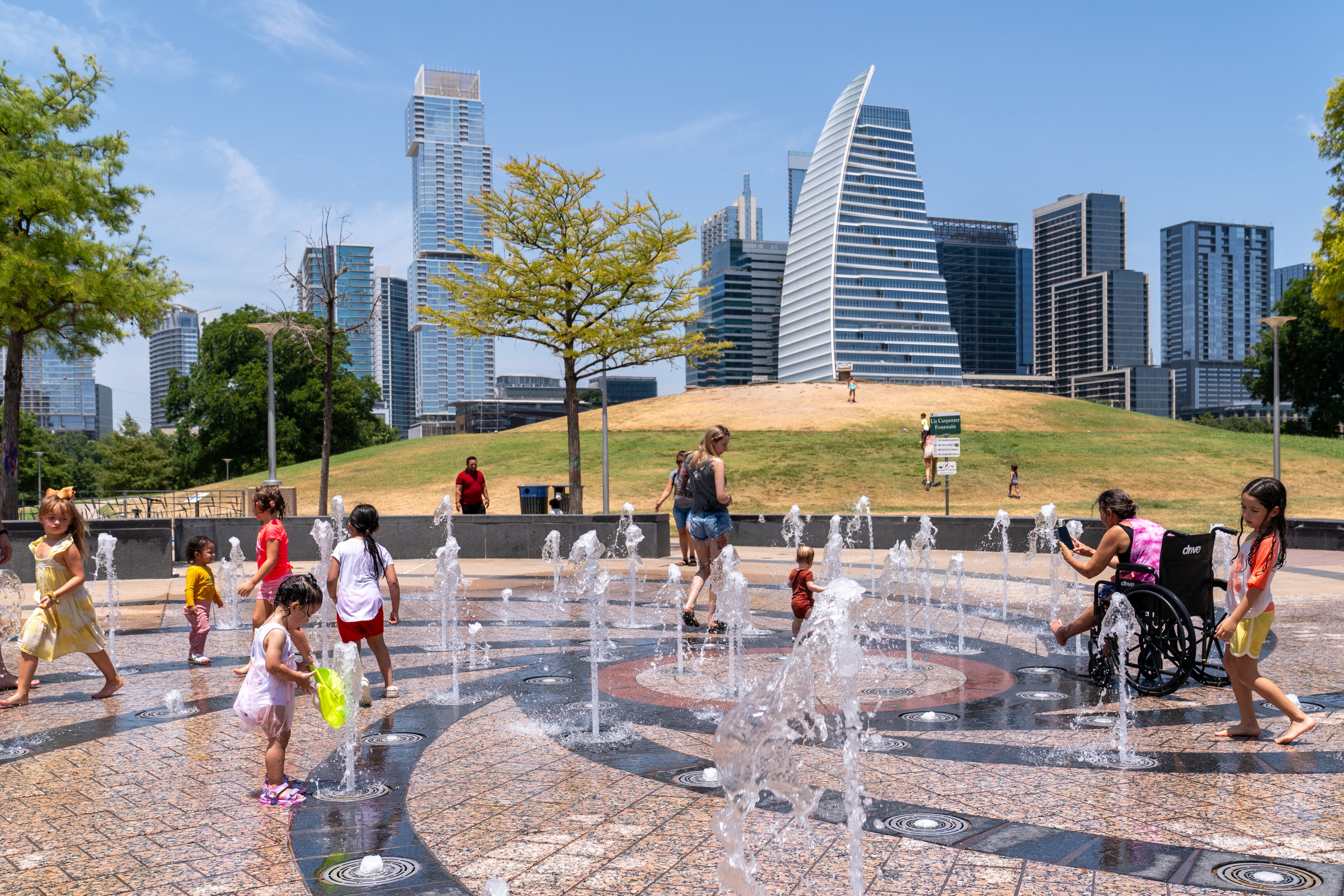 Residents cool off in the Liz Carpenter Splash Pad at Butler Park on July 16, 2023 in Austin, Texas, during a heat wave. Tens of millions of Americans braced for more sweltering temperatures Sunday, July 16, as brutal conditions threatened to break records due to a relentless heat dome that has baked parts of the country all week. (Photo by SUZANNE CORDEIRO / AFP)