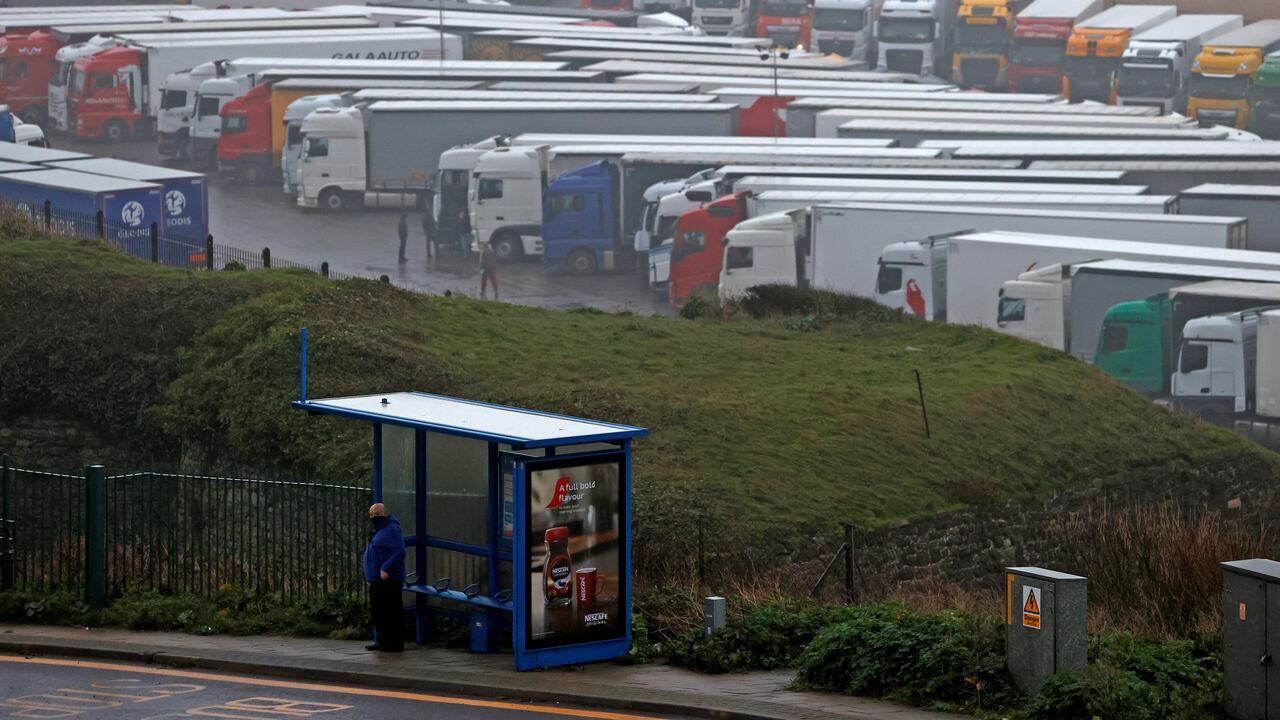 Un hombre se para en una parada de autobús mientras los camiones de carga y los vehículos de mercancías se muestran estacionados en un estacionamiento cerca del Puerto de Dover en Dover, Kent, en la costa sureste de Inglaterra el 21 de diciembre de 2020, como una serie de países prohibidos viajeros, todos excepto carga no acompañada que llega desde el Reino Unido, debido a la rápida propagación de una nueva cepa de coronavirus más infecciosa. El crítico puerto de la costa sur de Gran Bretaña en Dover dijo el domingo que cerraría para todos los pasajeros y carga acompañados debido a las restricciones de la frontera francesa "hasta nuevo aviso".
Adrian DENNIS / AFP