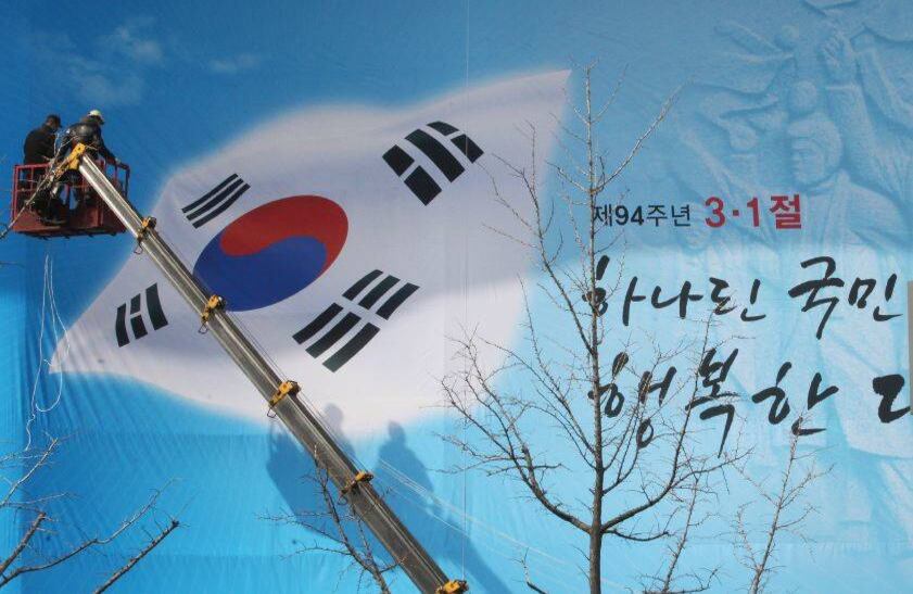 Con una grua, trabajadores cuelgan una pancarta que muestra la bandera frente al Centro de Cultura Sejong en Seúl, el 28 de febrero de 2013. FOTO: Ahn Young-joon/AP