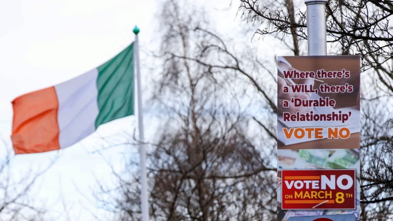 Se ven carteles de "No" en la calle frente a los edificios gubernamentales en Dublín, Irlanda, el 5 de marzo de 2024, antes del referéndum irlandés del viernes. Al fondo, la bandera del país. Irlanda se prepara para votar el viernes sobre las referencias constitucionales a la familia y el papel de la mujer en el hogar (Foto de PAUL FE / AFP)