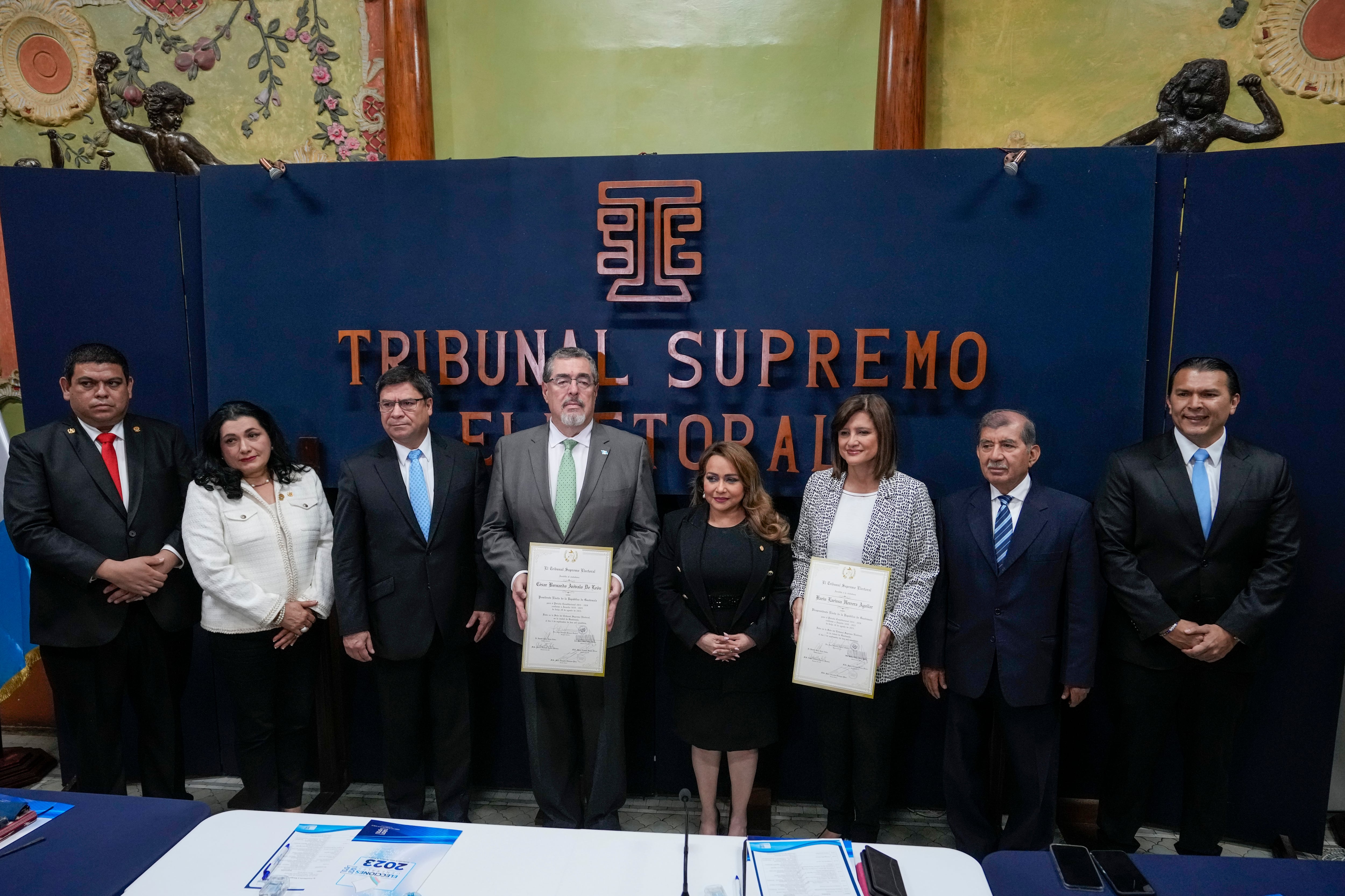 El presidente electo, Bernardo Arévalo, cuarto por la izquierda, y la vicepresidenta electa Karin Herrera, tercera por la derecha, posan con las credenciales de ganadores de las elecciones presidenciales, acompañados por miembros del Tribunal Supremo Electoral en Ciudad de Guatemala, el martes 5 de septiembre  de 2023. (AP Foto/Moisés Castillo)
