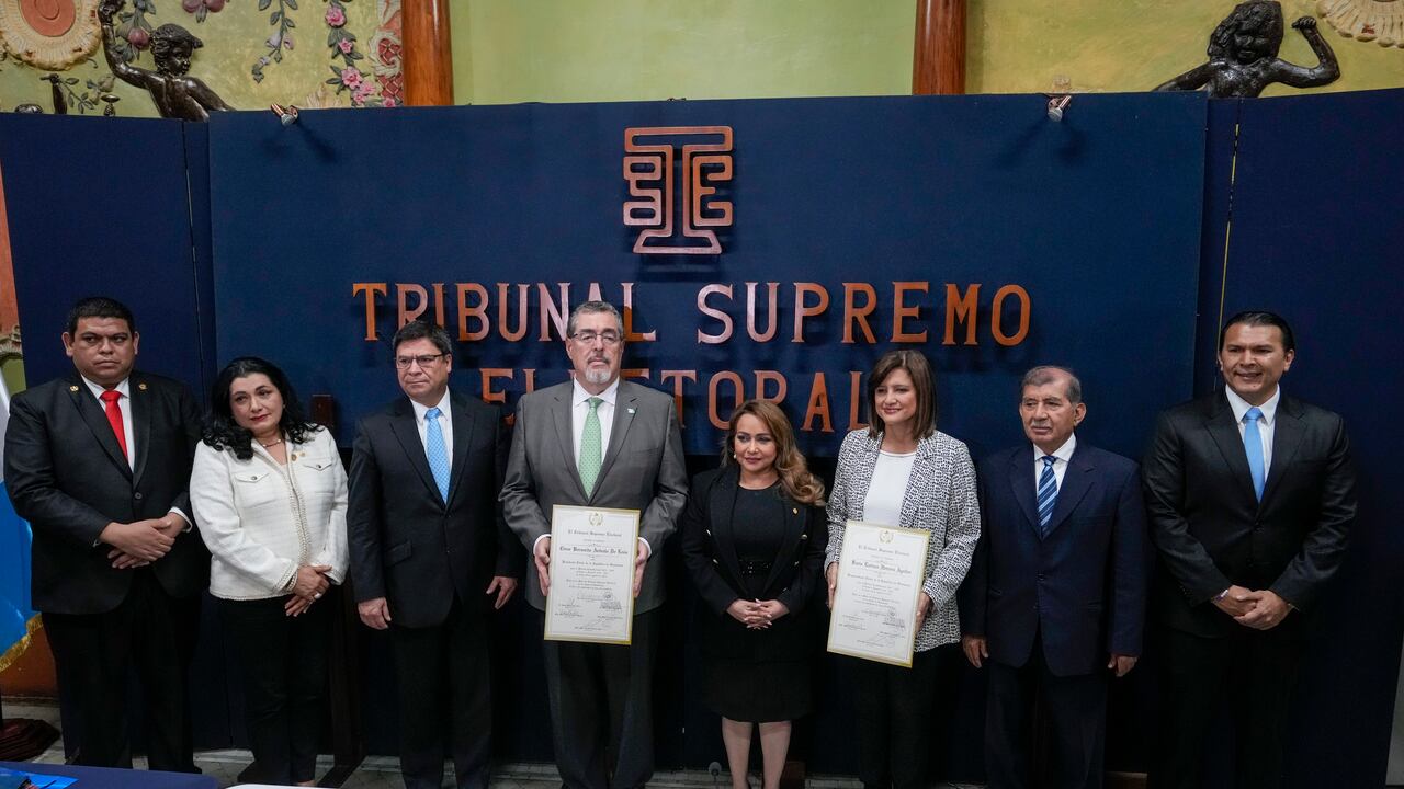 El presidente electo, Bernardo Arévalo, cuarto por la izquierda, y la vicepresidenta electa Karin Herrera, tercera por la derecha, posan con las credenciales de ganadores de las elecciones presidenciales, acompañados por miembros del Tribunal Supremo Electoral en Ciudad de Guatemala, el martes 5 de septiembre de 2023. (AP Foto/Moisés Castillo)