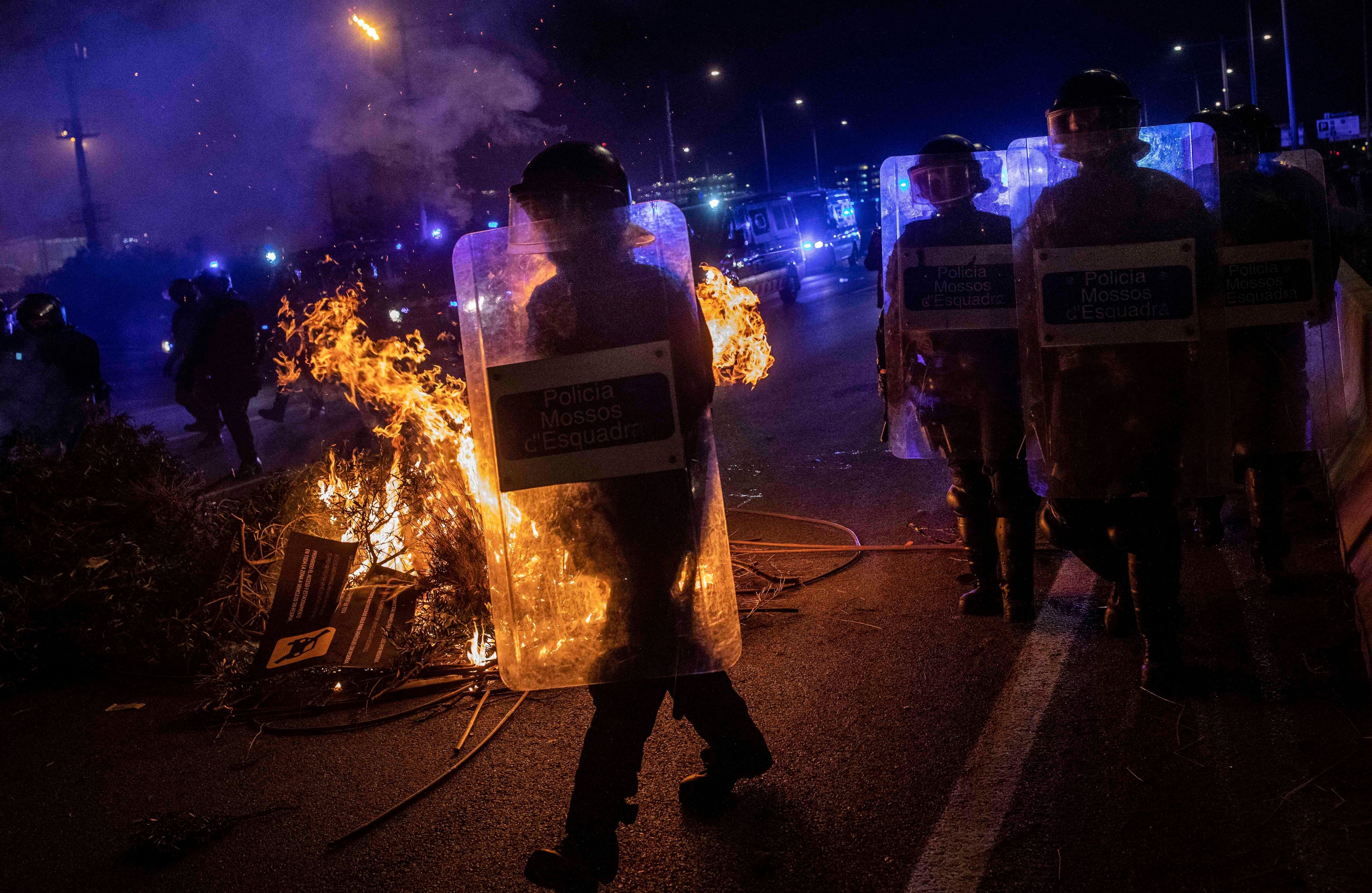 Un escuadrón de policía antimotines traspasa las barricadas de fuego que los manifestantes pusieron en el aeropuerto de El Prat  el lunes. Foto: AP. 