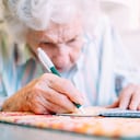 Ultra Close-Up Shot of an Elderly Senior Caucasian Woman's Hands As She Looks Close and Using a Pen to Write a Check