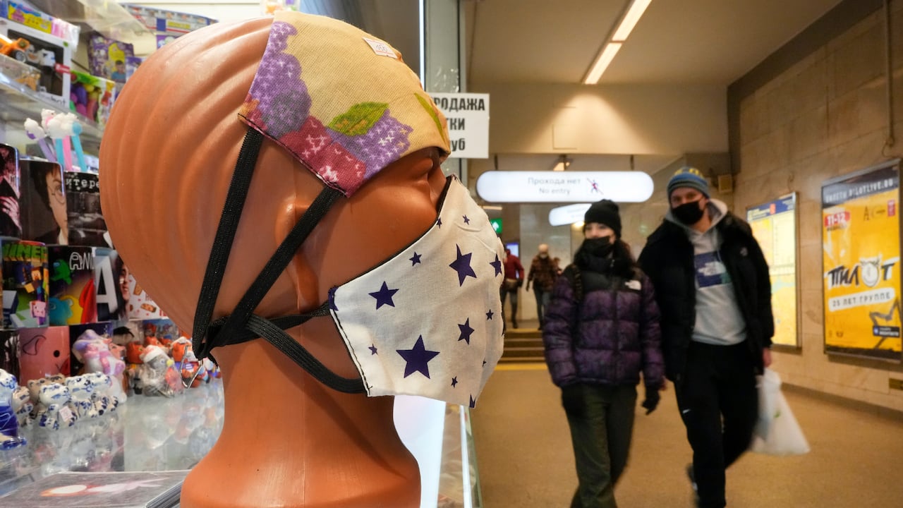 People walk past face masks displayed for sale in St. Petersburg, Russia, Monday, Jan. 24, 2022. Daily new coronavirus infections in Russia have reached an all-time high and authorities are blaming the highly contagious omicron variant, which they expect to soon dominate the country's outbreak. (AP Photo/Dmitri Lovetsky)
