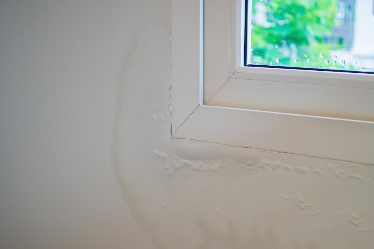 house wall near the window with some water stain show peeling paint